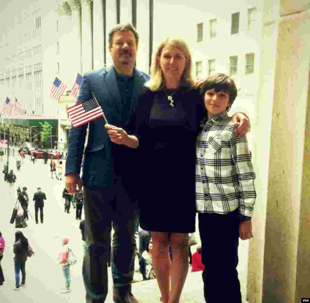 After the naturalization ceremony, Lesya Lysyj stands with her husband Bo and her son Lev on the steps of Federal Hall overlooking the New York Stock Exchange, May 22, 2014. (Adam Phillips/VOA)