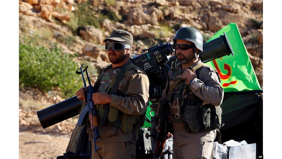 FILE - Hezbollah fighters stand on their army vehicle at the site where clashes erupted between Hezbollah and al-Qaida-linked fighters in Wadi al-Kheil or al-Kheil Valley in the Lebanon-Syria border, July 29, 2017.