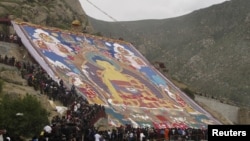 Tibetan Buddhists and tourists view a huge Thangka, a religious silk embroidery or painting displaying the Buddha portrait, during the Shoton Festival at Zhaibung Monastery in Lhasa, capital of southwest China's Tibet Autonomous Region, August 17, 2012.