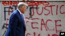 President Donald Trump walks by graffiti from protesters to visit St. John's Church Monday, June 1, 2020, in Washington. (AP Photo/Patrick Semansky)