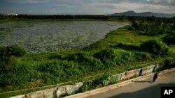A woman walks next to a highly contaminated pond around the grounds of the Danang airbase in Danang, Vietnam, May 21, 2007