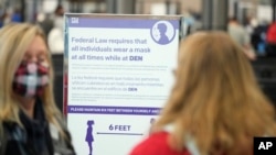 A sign advises travelers to don face coverings while in the terminal of Denver International Airport, Dec. 26, 2021. 