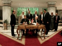 FILE - Senior Fatah official Azzam al-Ahmad, center right, and Hamas' representative, Saleh al-Arouri, center left, sign a reconciliation deal during a short ceremony at the Egyptian intelligence complex in Cairo, Egypt, Oct. 12, 2017.