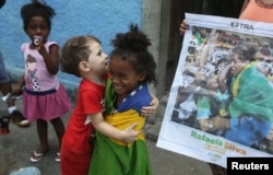 FILE - Cousins of Brazilian Judoka Rafaela Silva who won the gold medal in the 57 kg judo final, joke beside a newspaper with the picture of her next to the house where she was born at the City of God slum.