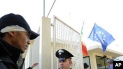 A would-be immigrant is escorted to register at a re-opened detention center on the island of Lampedusa, Italy, Sunday, Feb. 13, 2011.