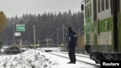 Rescue and military personnel and a policeman are seen at the railroad crossing after a crash between a train and a military truck in southern Finland, Oct. 26, 2017.