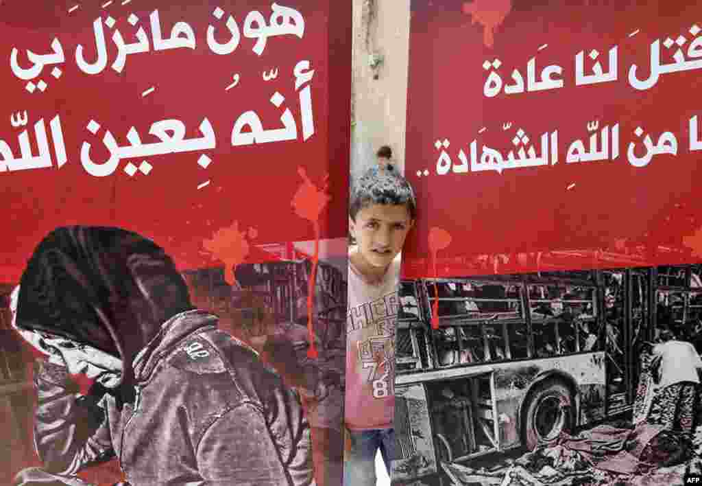 A child looks out from behind posters during a funeral ceremony in the Sayyida Zeinab mosque on the outskirts of Damascus, Syria.