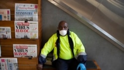 A masked newspaper seller waits to make a sale in the virtually empty Rosebank Mall in Johannesburg, March 22, 2020.
