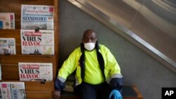 A masked newspaper seller waits to make a sale in the virtually empty Rosebank Mall in Johannesburg, March 22, 2020.