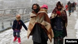 Syrian refugees brave the cold and snow as they walk to a metro station in Istanbul February 11, 2015, at the start of a day's begging. The civil war, which began as a popular uprising against President Bashar al-Assad in March 2011, has killed 200,000 pe