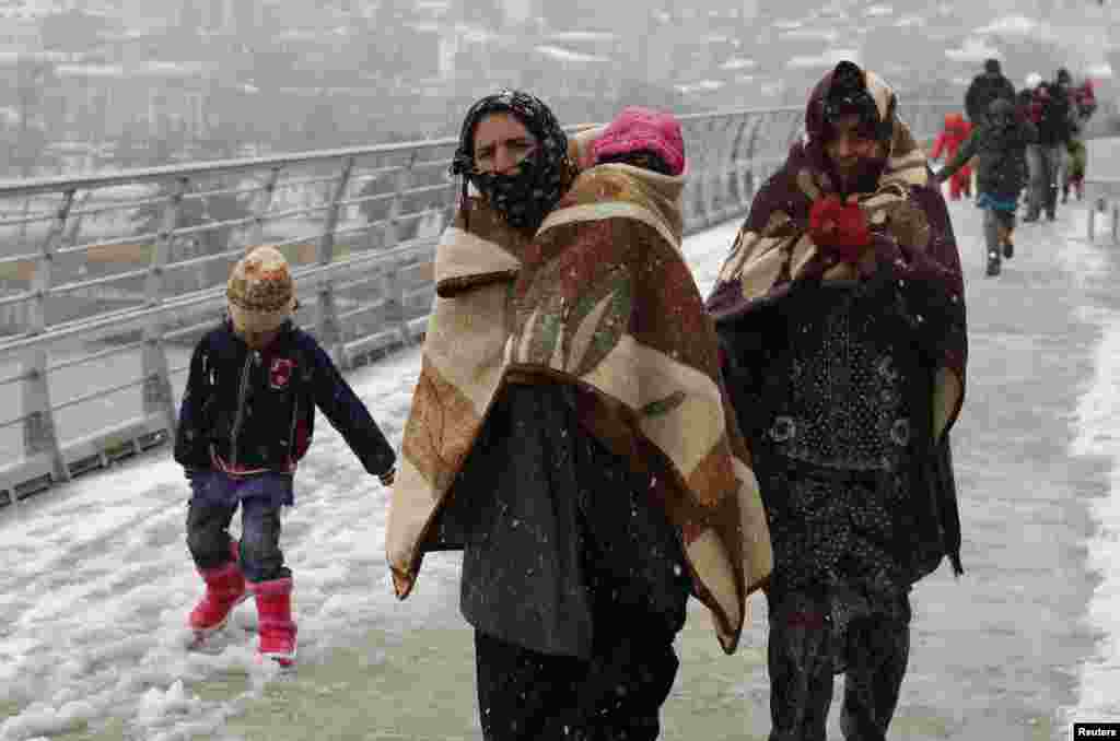 Pengungsi Suriah melawan udara dingin dan hujan salju berjalan di stasiun kereta di Istanbul, Turki.