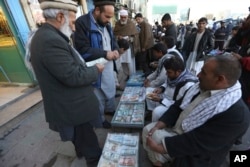 An Afghan money changer, second from right, counts a pile of Pakistani currency banknotes at a money exchange market in Kabul, Dec. 5, 2016.