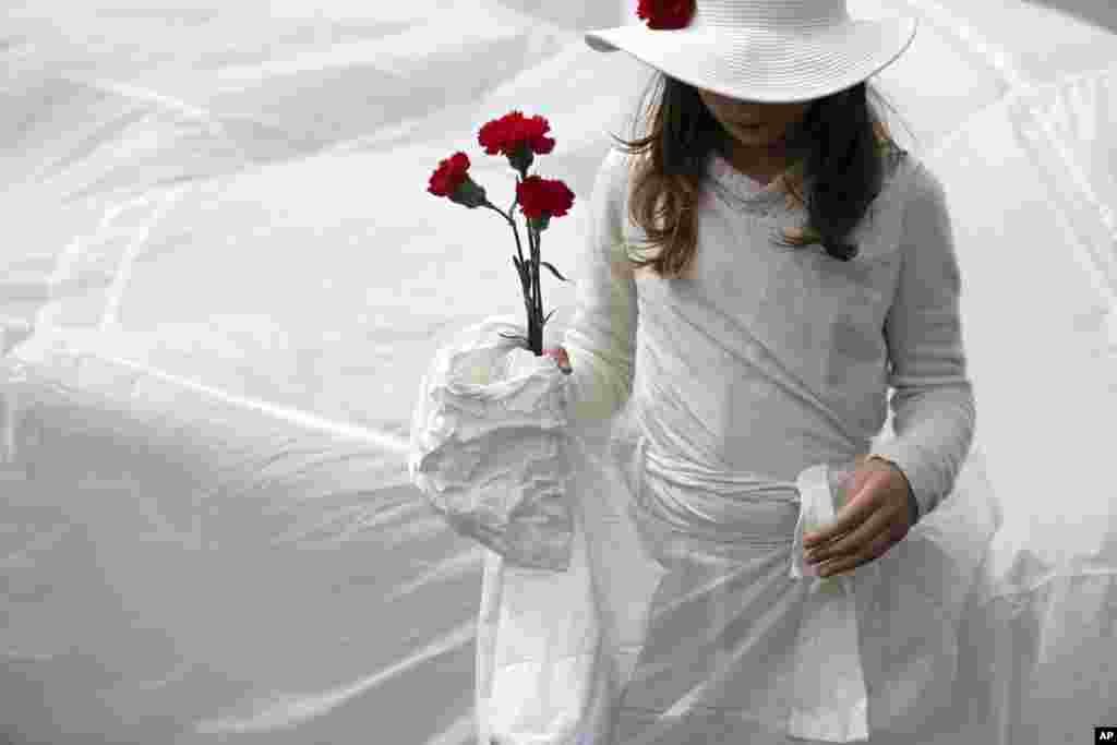 A girl from a group of performers carries red carnations while taking part in a parade celebrating the April 25, 1974 revolution, also known as the Revolution of the Carnations.