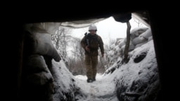 A Ukrainian Military Forces serviceman walks along a snow covered trench on the front line with the Russia-backed separatists near Zolote village, in the eastern Lugansk region, on Jan. 21, 2022.