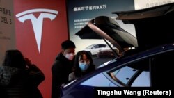 FILE - Visitors wearing face masks check a China-made Tesla Model Y sport utility vehicle (SUV) at the electric vehicle maker's showroom in Beijing, China on January 5, 2021. (REUTERS/Tingshu Wang/File Photo)