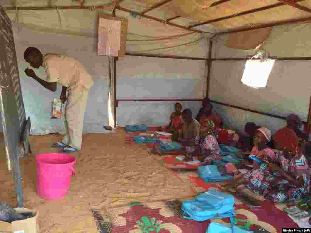 Munis de fournitures données par l'Unicef, ces écoliers du camp de Ngourtoua écoutent leur instituteur, à Diffa, le 1er mars 2016. (VOA/Nicolas Pinault)