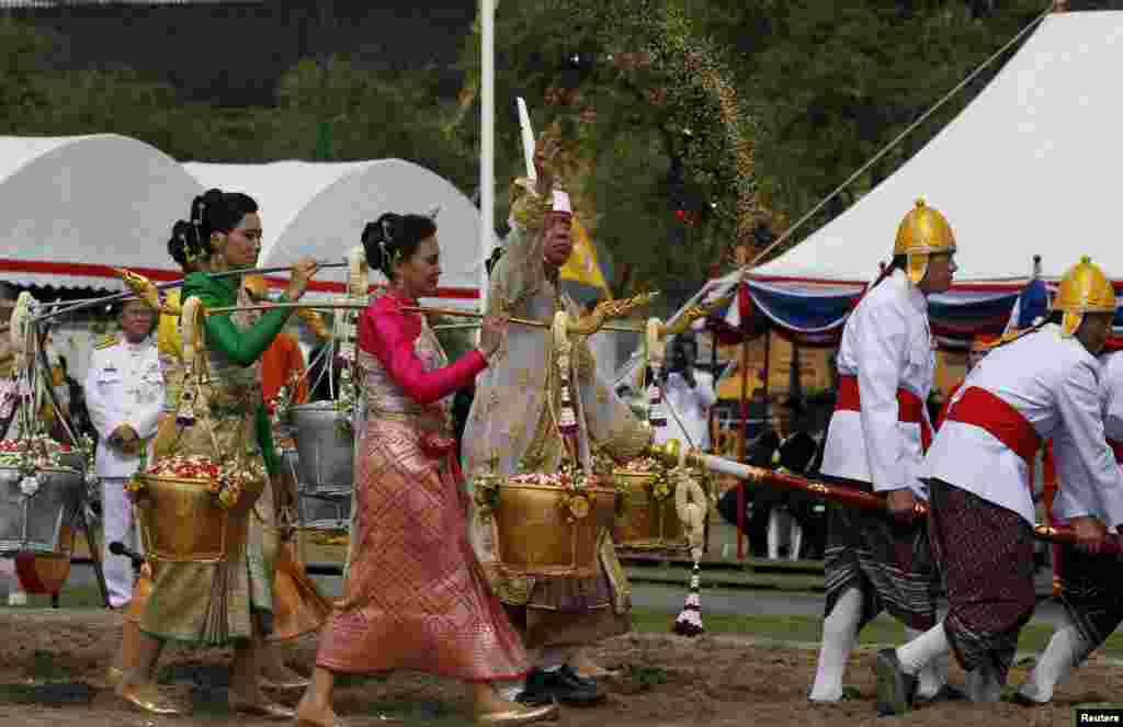 Chavalit Chookajorn, sekertaris permanen Departemen Pertanian dan Kooperasi Thailand, berpakaian kostum tradisional, menerima butir beras dalam upacara pembajakan tanah tahunan di Bangkok tengah, Thailand. Upacara kuno itu diawasi oleh Putra Mahkota Maha Vajiralongkorn, menandai akhir dari musim kering dan dimaksudkan untuk menyambut awal musim tanam yang bertuah.