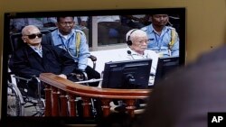 Khieu Samphan, second from right, former Khmer Rouge head of state, and Noun Chea, left, who was the Khmer Rouge's chief ideologist and No. 2 leader, is seen on a screen at the court's press center of the U.N.-backed war crimes tribunal in Phnom Penh, Cambodia.