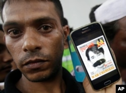 A Rohingya protester shows his mobile phone displaying a portrait of Myanmar's Foreign Minister Aung San Suu Kyi with her mouth covered with a sandal during a demonstration in front of the Myanmar Embassy in Bangkok, Thailand, Nov. 25, 2016.