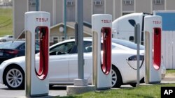 FILE - A Tesla electric vehicle charges at a station in Topeka, Kansas, April 5, 2021.