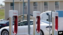 FILE - A Tesla electric vehicle charges at a station in Topeka, Kansas, April 5, 2021.