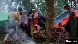 Rohingya refugees go about their day outside their temporary shelters along a road in Kutupalong, Bangladesh, Sept. 9, 2017.