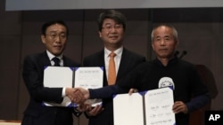 Hwang Sang-gi, padre de la ex trabajadora de la fábrica de semiconductores de Samsung Hwang Yu-mi quien murió de leucemia en 2007, Kinam Kim, presidente y director ejecutivo de Samsung Electronics y Kim Ji-hyung, presidente del Comité de Mediación firman un documento en Seúl el viernes.