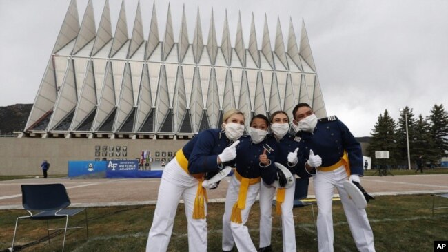 Frente a la capilla de la Academia de la Fuerza Aérea de EE.UU., cadetes con máscaras faciales posan para los fotógrafos después de su ceremonia de graduación. Sábado 18 de abril de 2020, Colorado Springs, Colorado.
