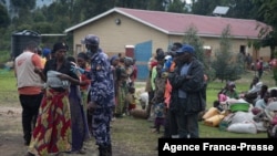 FILE - A Ugandan police officer speaks to a group of asylum seekers from the Democratic Republic of the Congo at a transit center in Kisoro, Uganda, Nov. 10, 2021. Uganda is deploying troops in the DRC in a joint operation against ADF rebels.
