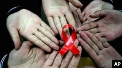 Chinese students show a handmade red ribbon one day ahead of the the World AIDS Day, 30 Nov 2009