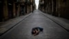Seorang pria tidur di tengah jalan yang sepi di Barcelona, Spanyol, saat diberlakukannya karantina wilayah tersebut, 17 April 2020. (Foto: dok).