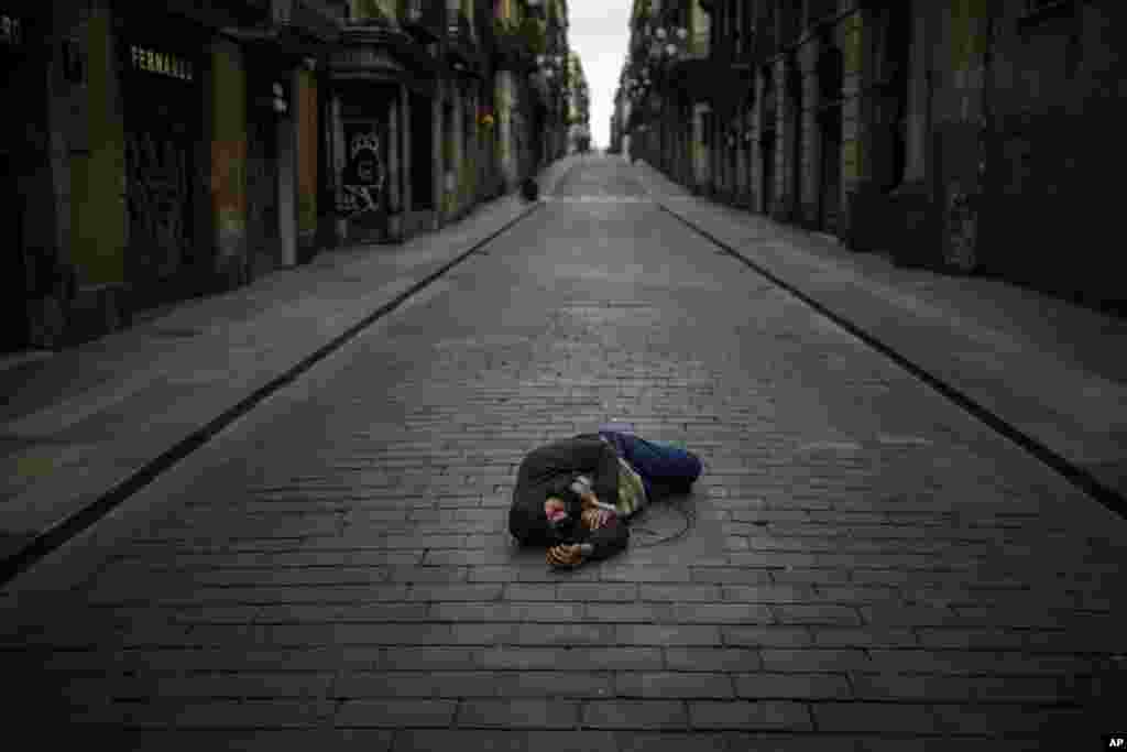 A man sleeps in an empty street during the coronavirus outbreak in Barcelona, Spain.