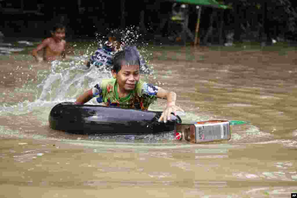 A boy rides an inner tube as he swims in a flooded road in Bago, northeast of Yangon, Aug. 1, 2015.