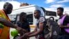 Jacob Maphala, un regulador de taxis con una máscara facial, rocía desinfectante a los pasajeros para protegerse contra el coronavirus, en una estación de taxis en Johannesburgo, Sudáfrica. Marzo 26 de 2020.
