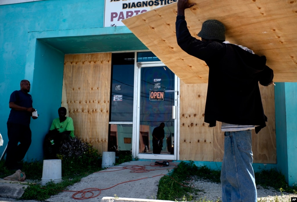 Los trabajadores tapan el escaparate de una tienda mientras se preparan para la llegada del huracán Dorian, en Freeport, Bahamas, el viernes 30 de agosto de 2019. Los meteorólogos dijeron que se espera que el huracán continúe fortaleciéndose. (Foto AP / Ramon Espinosa).