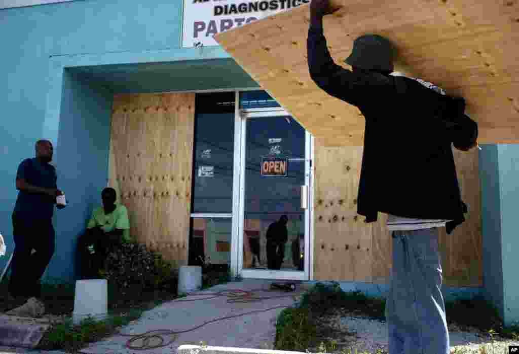 Los trabajadores tapan el escaparate de una tienda mientras se preparan para la llegada del huracán Dorian, en Freeport, Bahamas, el viernes 30 de agosto de 2019. Los meteorólogos dijeron que se espera que el huracán continúe fortaleciéndose. (Foto AP / Ramon Espinosa).