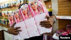 A worker carries barbie dolls to put them on the shelves at a toy store in Caracas, Venezuela, Nov. 14, 2014. 