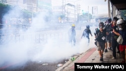Reporters stand to the side of an anti-government protest as demonstrators standoff with police who fired tear gas, Bangkok, Thailand, Aug. 7 2021.