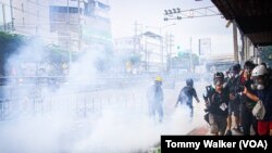 Reporters stand to the side of an anti-government protest as demonstrators standoff with police who fired tear gas, Bangkok, Thailand, August 7 2021.