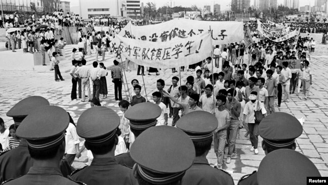 FILE - Chinese police monitor a march by tens of thousands of pro-democracy protesters in the special economic zone of Shenzhen in southern China, May 22,1989. Hundreds of people were killed in Beijing on June 4, 1989, when Chinese troops crushed month-lo