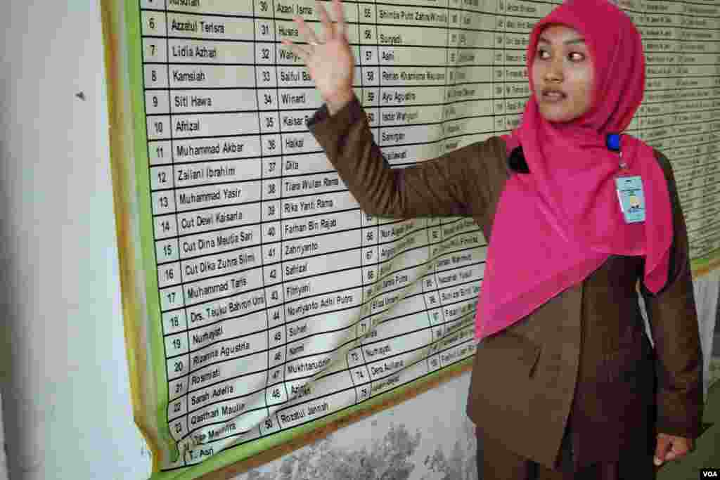 Salmi Hardiyanti, 24, menunjukkan nama-nama sembilan kerabatnya yang tewas akibat tsunami dan jenazahnya tidak pernah ditemukan. (VOA/Steve Herman)