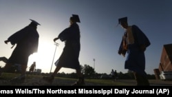 In this June 27, 2020, file photo, Saltillo High School seniors make their way to the football field as the sun begins to set for their graduation ceremony in Saltillo, Mississippi.