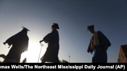 In this June 27, 2020, file photo, Saltillo High School seniors make their way to the football field as the sun begins to set for their graduation ceremony in Saltillo, Mississippi. (Thomas Wells/The Northeast Mississippi Daily Journal via AP, File)