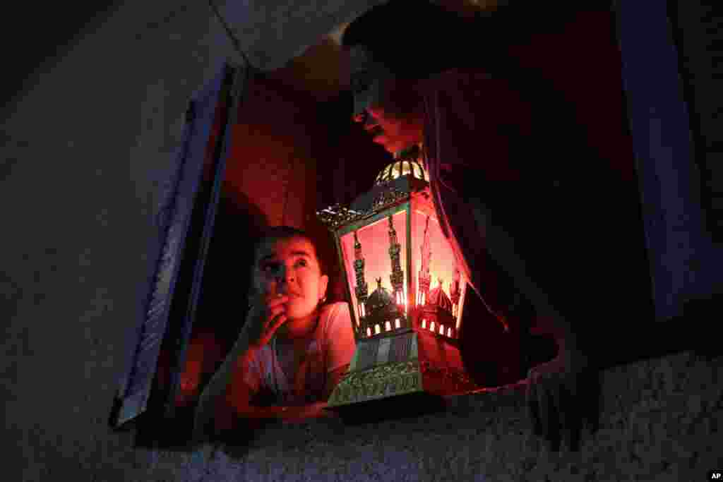 Egyptian children hold a traditional Ramadan lantern placed in a windowsill during the holy month of Ramadan in Cairo, Egypt.