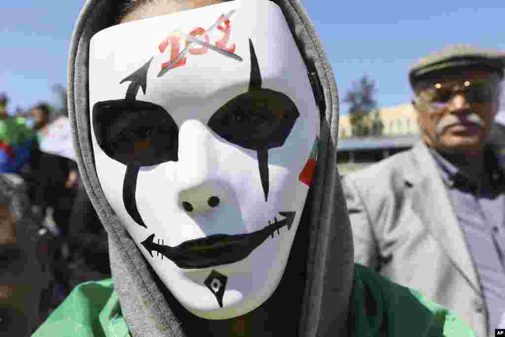 A demonstrator wears a mask with signs on it referring to Article 102 of the constitution, which paves the way to ouster President Abdelaziz Bouteflika, during a protest in Algiers, Algeria.
