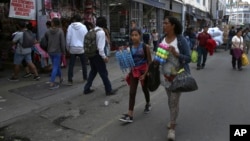 Venezuelan Sandra Cadiz and her 10-year-old daughter Angelis walk try to sell cotton swabs and razors near the Central Market in Lima, Peru, Oct. 9, 2018. 