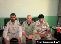 In this undated photo provided by Ryan Brummond, U.S. Special Forces Officer Ryan Brummond, center, is seated next to Mohammad Khalid Wardak, right, in Afghanistan.