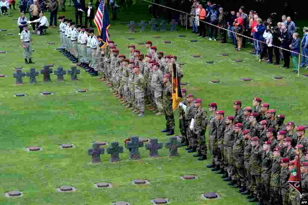 German, Canadian, Polish, French, and US soldiers take part in a ceremony at the Normandy German cemetery in La Cambe as part of D-Day commemorations marking the 75th anniversary of the World War II Allied landings in Normandy.