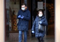 Personas con máscaras protectoras que salen de un supermercado.