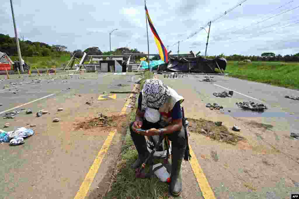 An indigenous demonstrator looks at his mobile phone near a barricade blocking the Panamerican highway during a protest against the government triggered by a now abandoned tax reform bill, in Cali, Colombia.